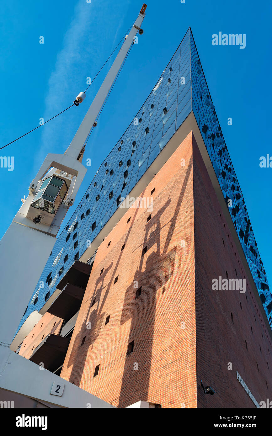 Eine Ecke der Elbphilharmonie auf dem Kaispeicher A mit dem Schatten der Kräne auf der Mauer vor strahlend blauem Himmel Stock Photo