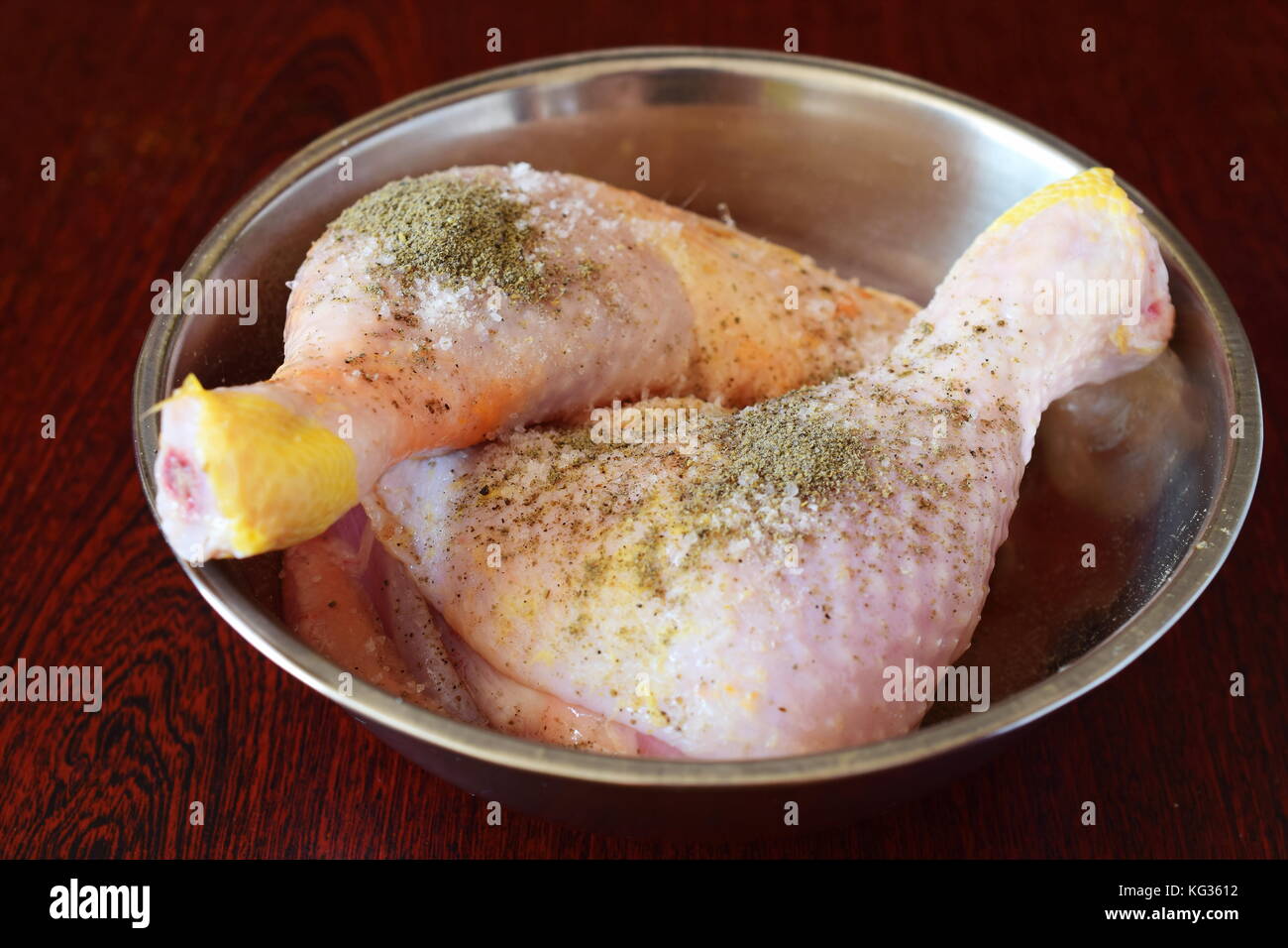 Chicken legs in a metal bowl with salt and pepper, vinegar . Step by