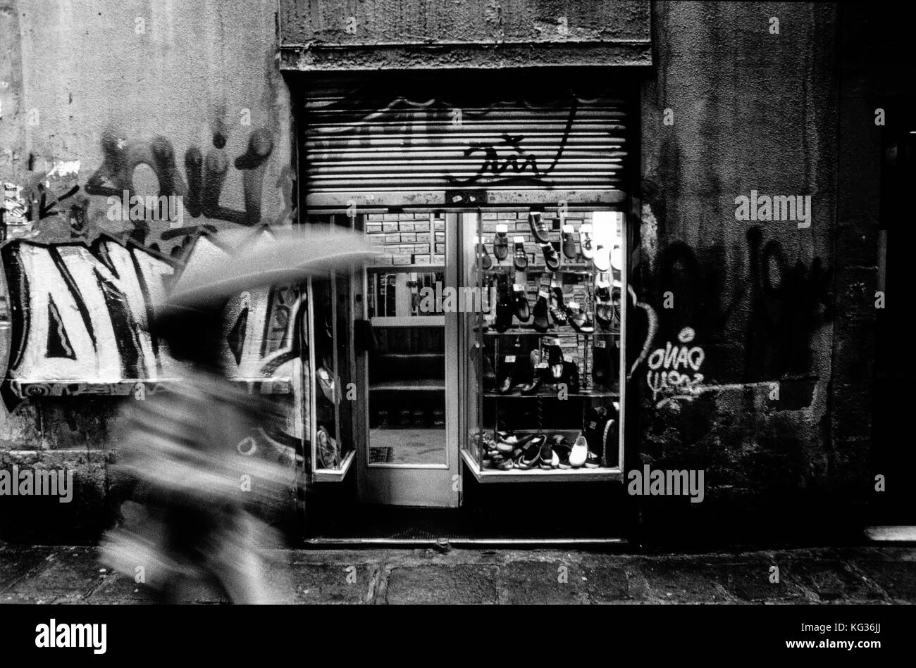 A women walks by one of the entrances from the extinct shoe shop Calçats Mila in the Carme street of Barcelona, Spain. Date: 02/2003. Photo: Xabier Mikel Laburu. The shoe shop Calçats Mila is documented with an other name in 1846. In the beginnings of the XX century, the shop is sold to the Mila family who would take care of it until the death of Roser, the last owner after her brother Joan Mila, who would have the tough job to close the shop in 2003. Stock Photo