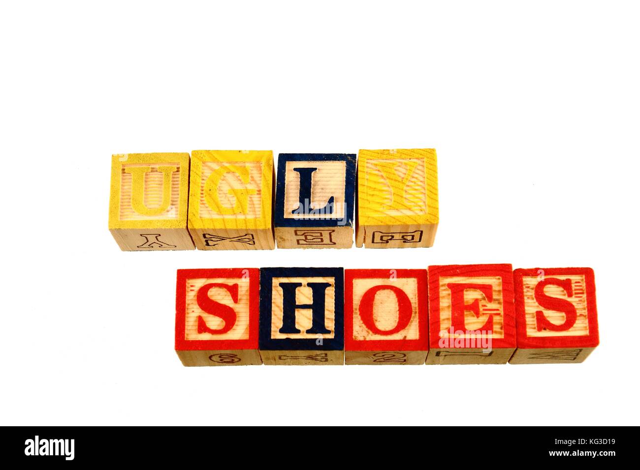 The term ugly shoes visually displayed on a white background using colorful wooden toy blocks in landscape format with copy space Stock Photo