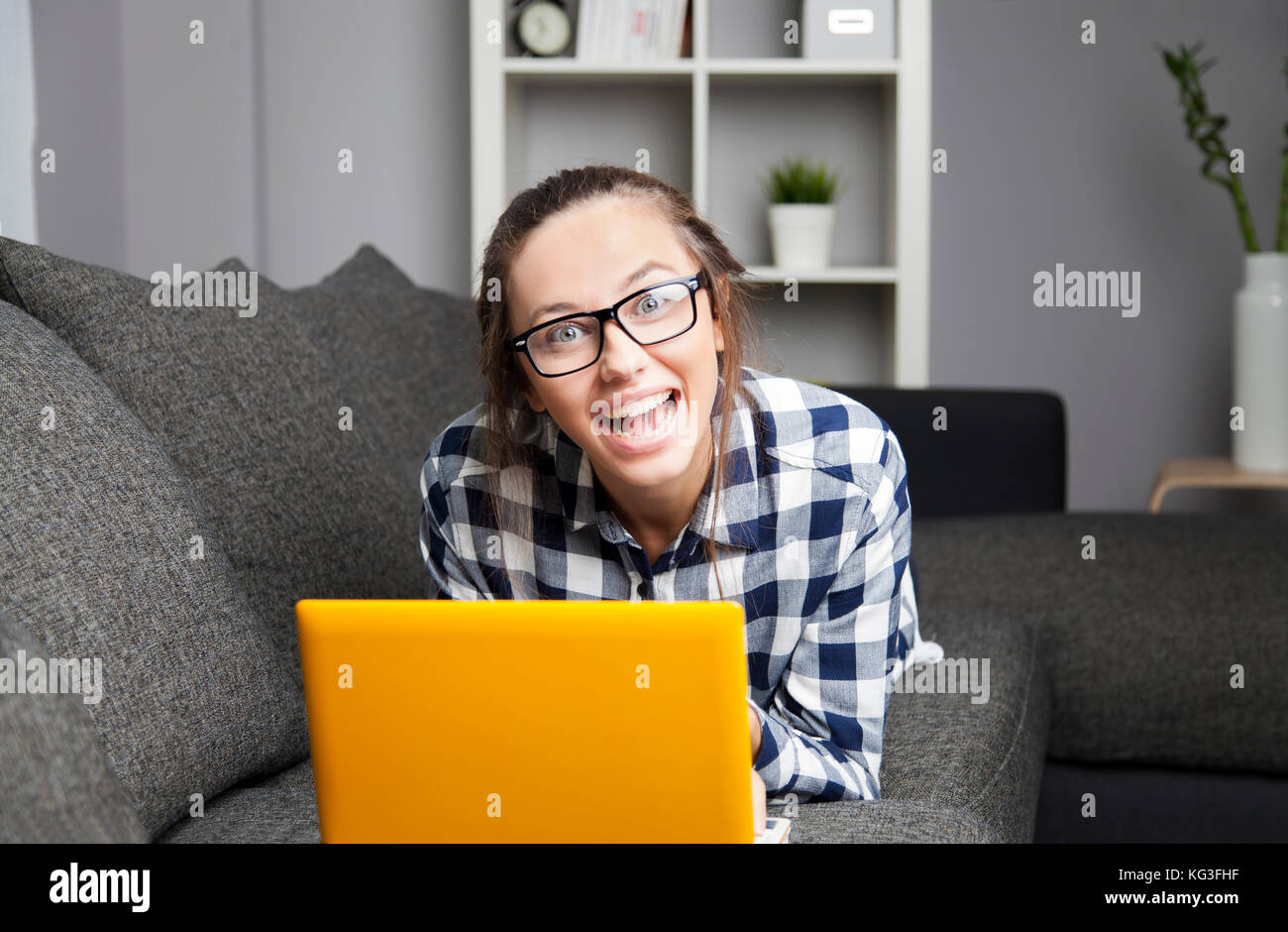 Happy funny young woman is using her laptop in the living room Stock Photo