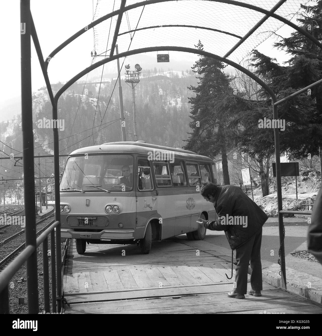 1950s, historical, mini-coach boarding or driving onto the flat deck of a car-carrier railway wagon to be transported, Trentino, Italy. This form of motorail travel was popular in Europe at this time. Stock Photo