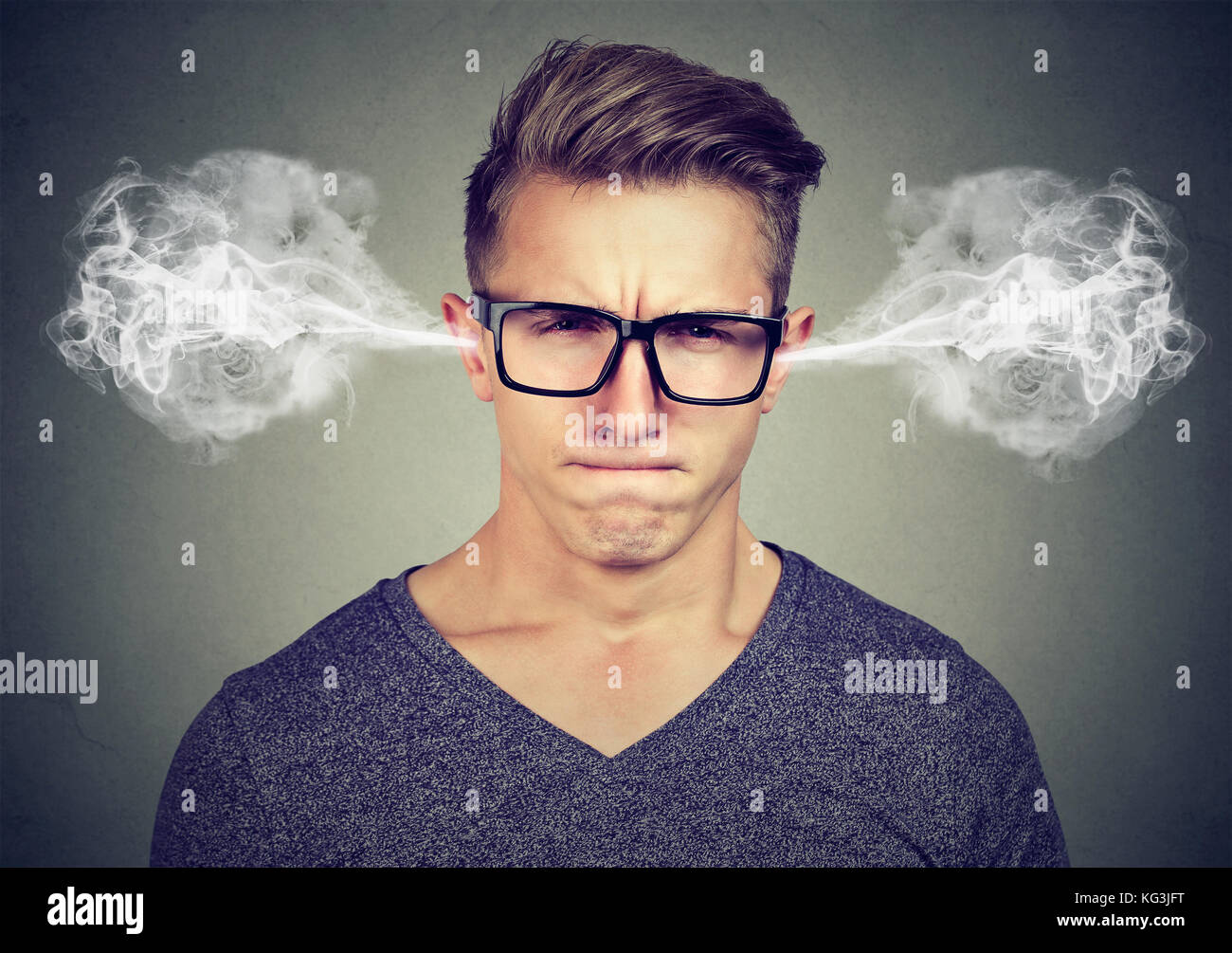 Angry young man, blowing steam coming out of ears, about to have nervous breakdown isolated on gray background. Negative human emotions facial express Stock Photo