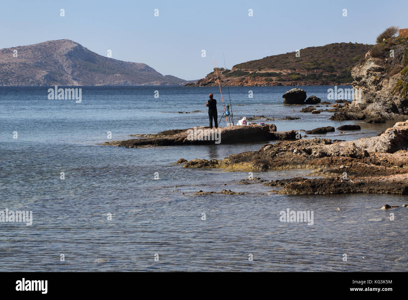 Attica Greece Sounion Beach Man fishing in sea Stock Photo