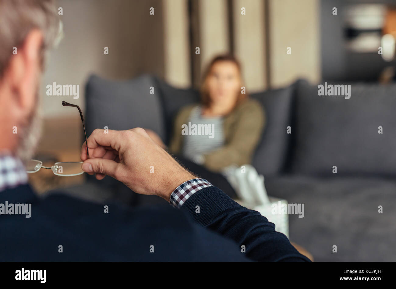 Hands of psychologist holding glasses and listening to woman in trouble during therapy session. Psychotherapist understanding problems of a woman pati Stock Photo