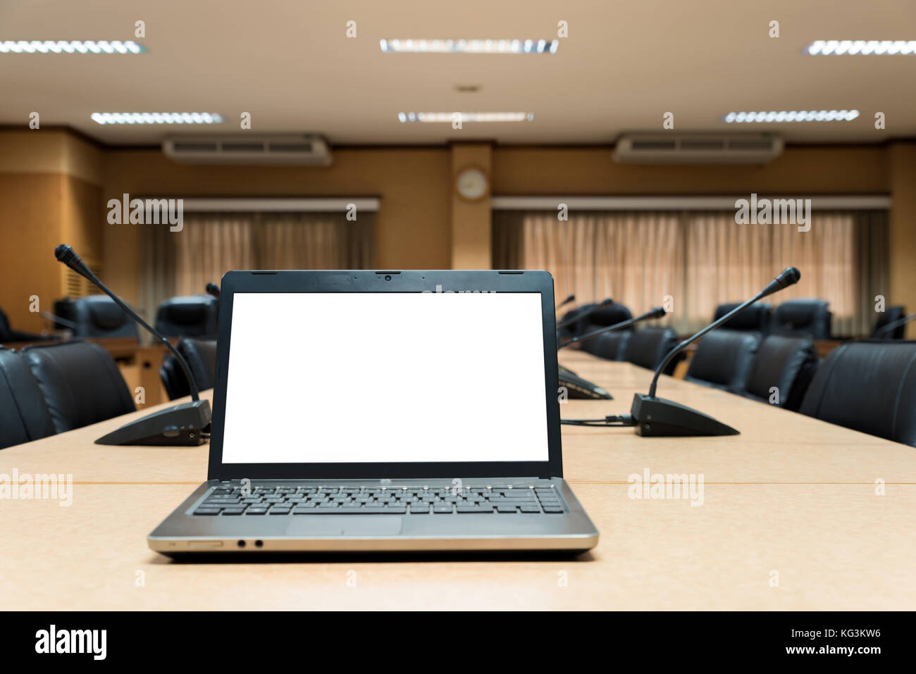 White Blank laptop computer placed on wooden meeting table in empty meeting room. Stock Photo