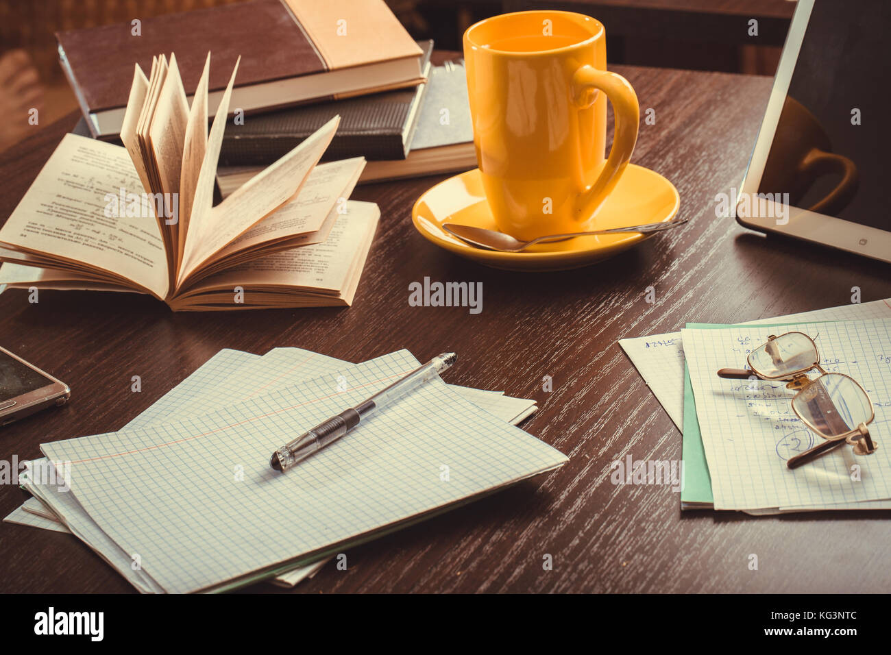 Working disorder on a desk. Notebook, book, points, handle, notes, cup ...