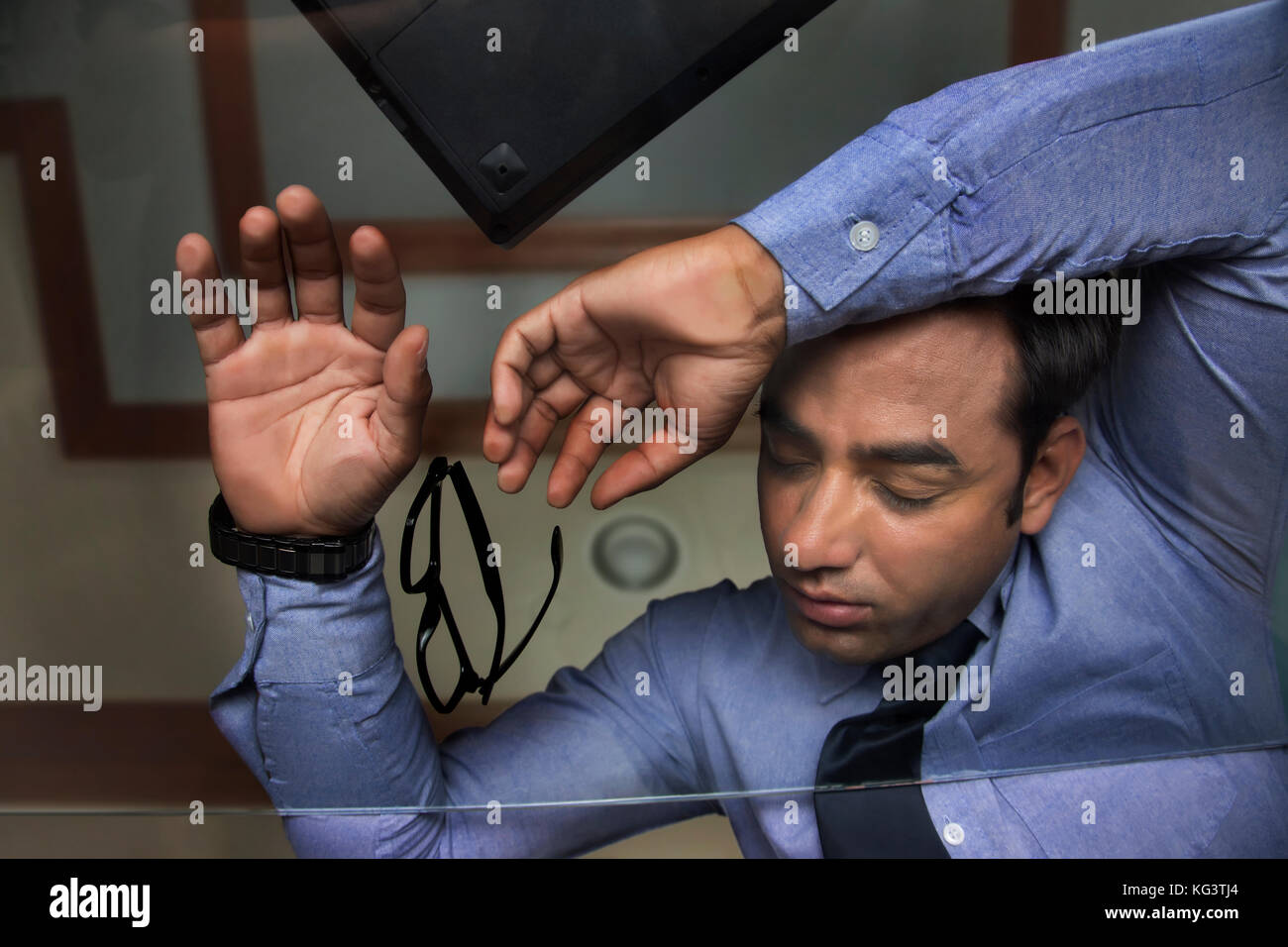 Businessman sleeping on glass table in office Stock Photo