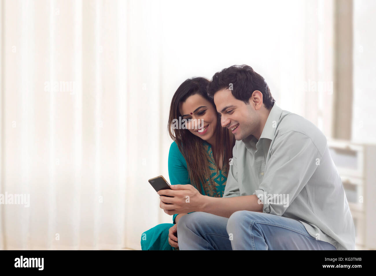 Smiling couple looking at mobile phone Stock Photo