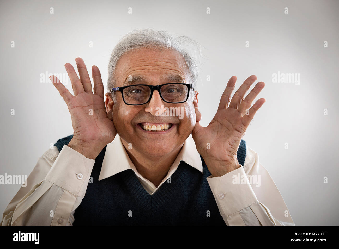 Senior man making funny face with hands in his ears Stock Photo