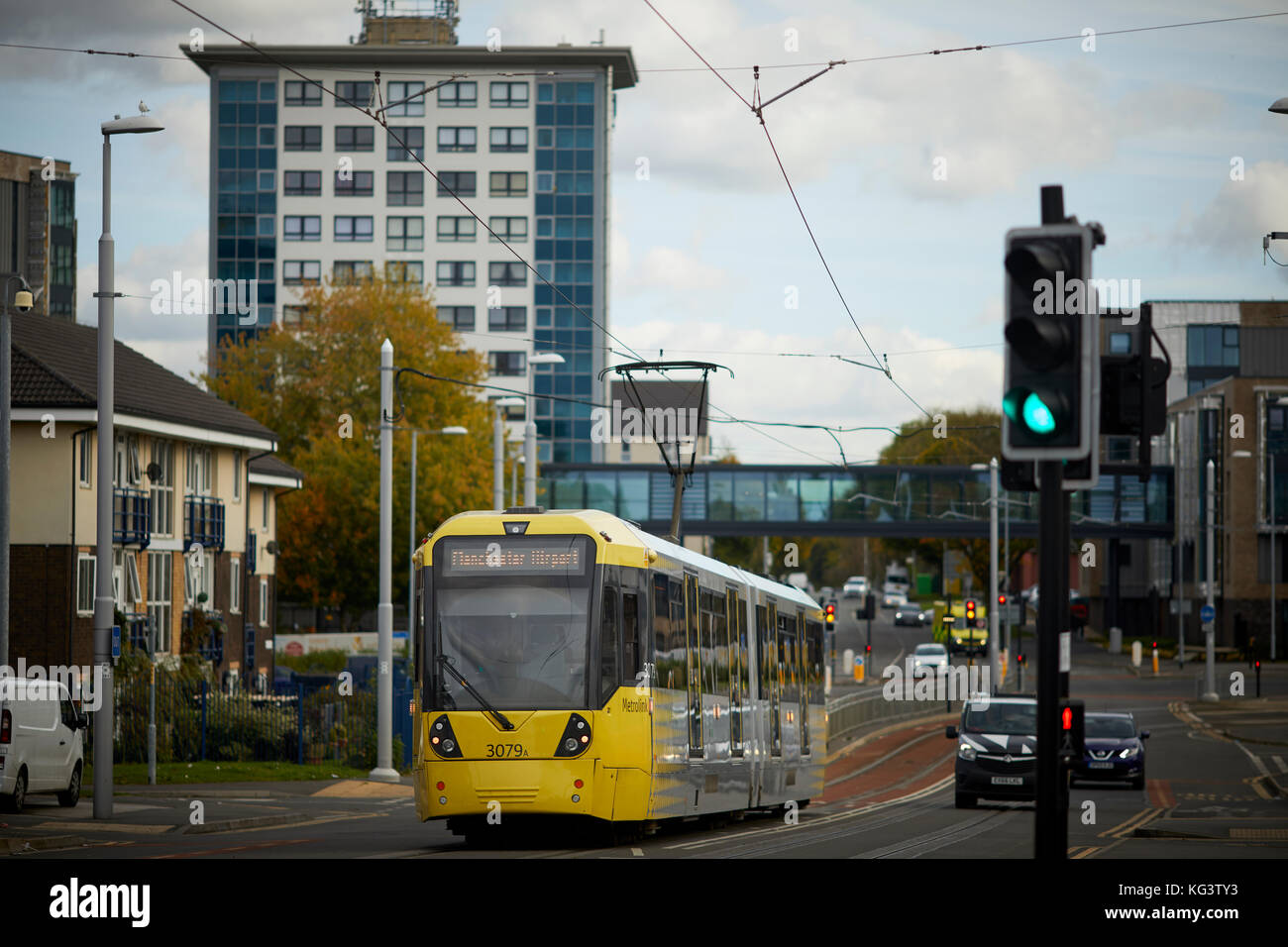 A yellow Metrolink Manchester tram at Hollyhedge Road, Benchill, Wythenshawe. Village 135 retirement housing for the over 55's Stock Photo