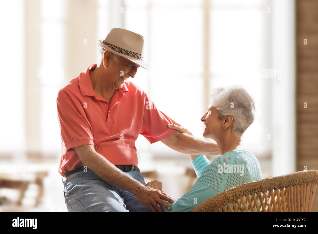 Smiling senior couple holding hands sitting together and talking Stock Photo