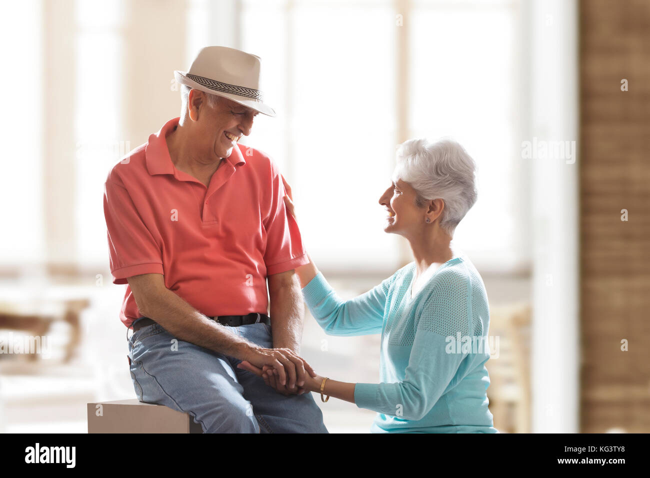 Happy senior couple sitting together holding hands and talking Stock Photo