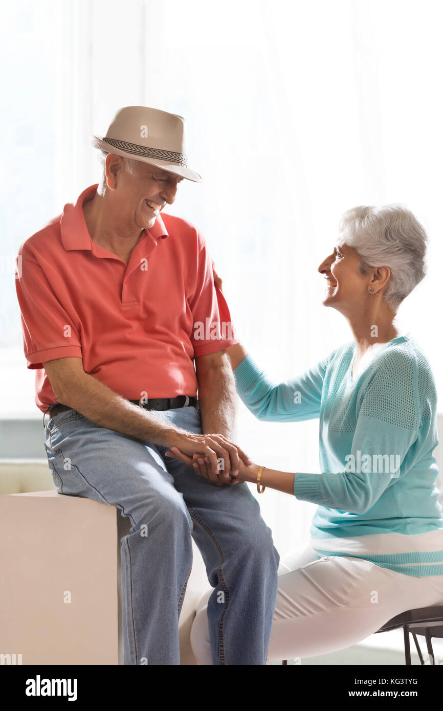 Happy senior couple holding hands sitting together and talking Stock Photo