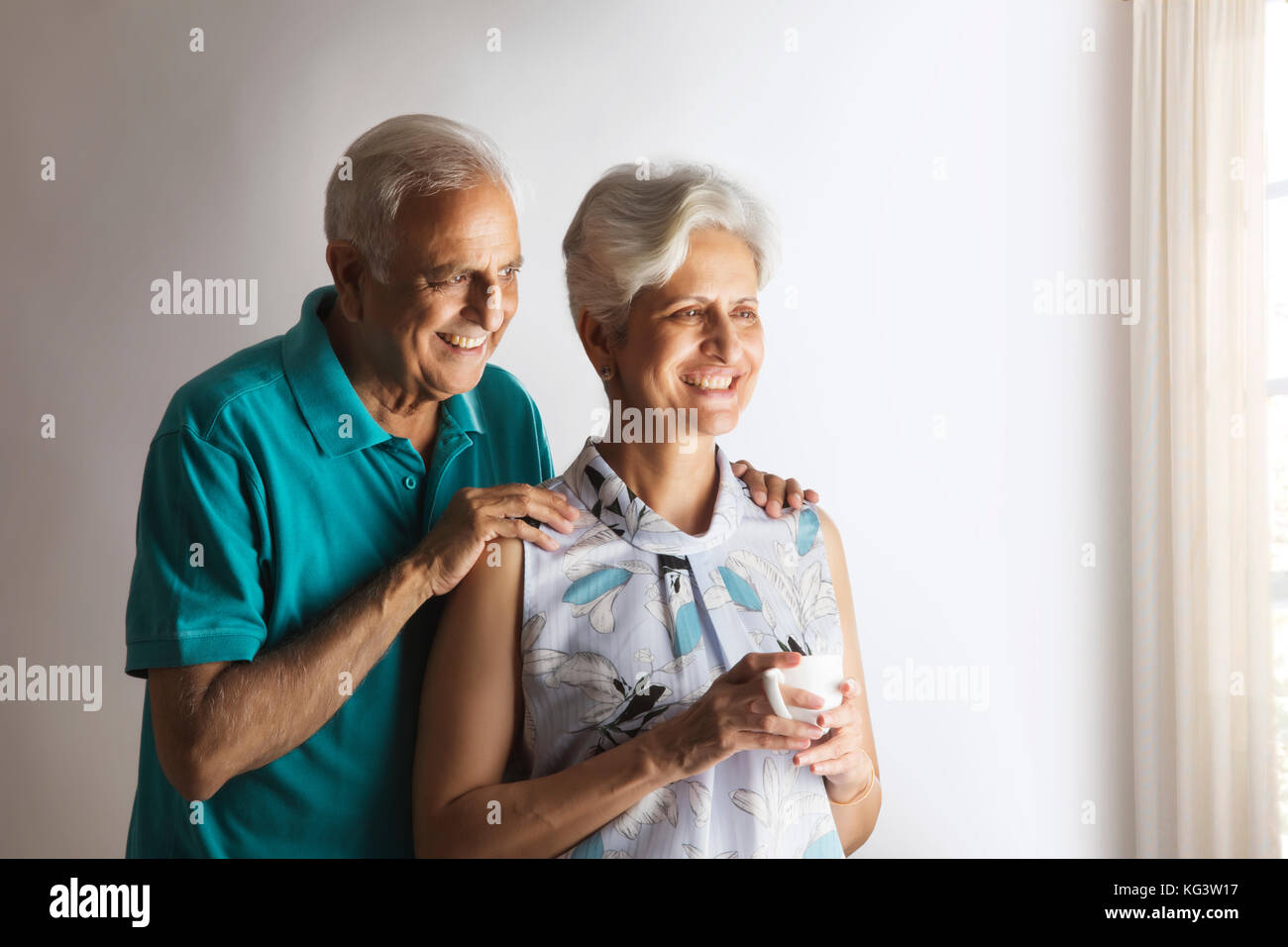 Thoughtful senior couple having tea looking through window Stock Photo