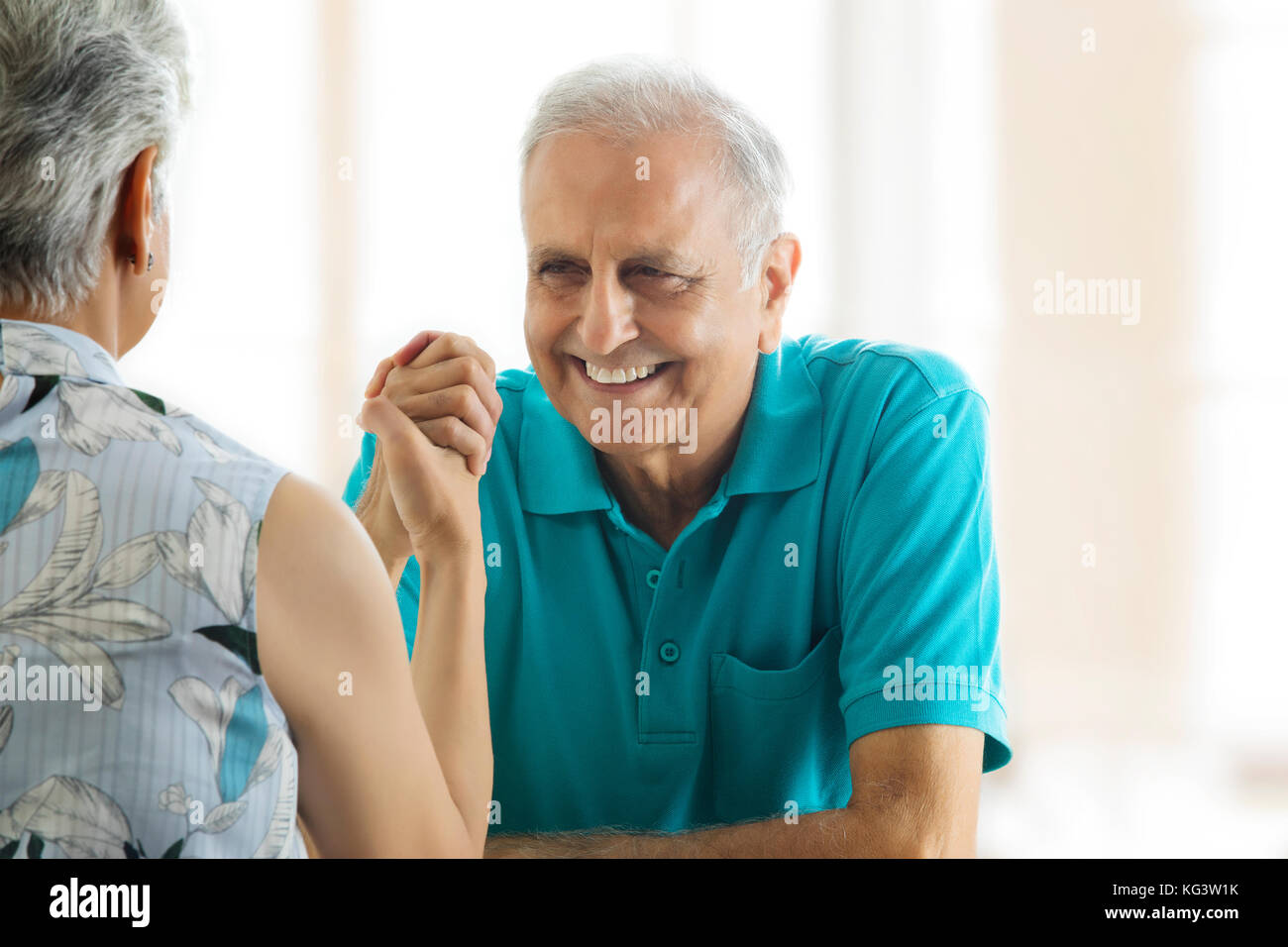 Senior couple arm wrestling at table Stock Photo