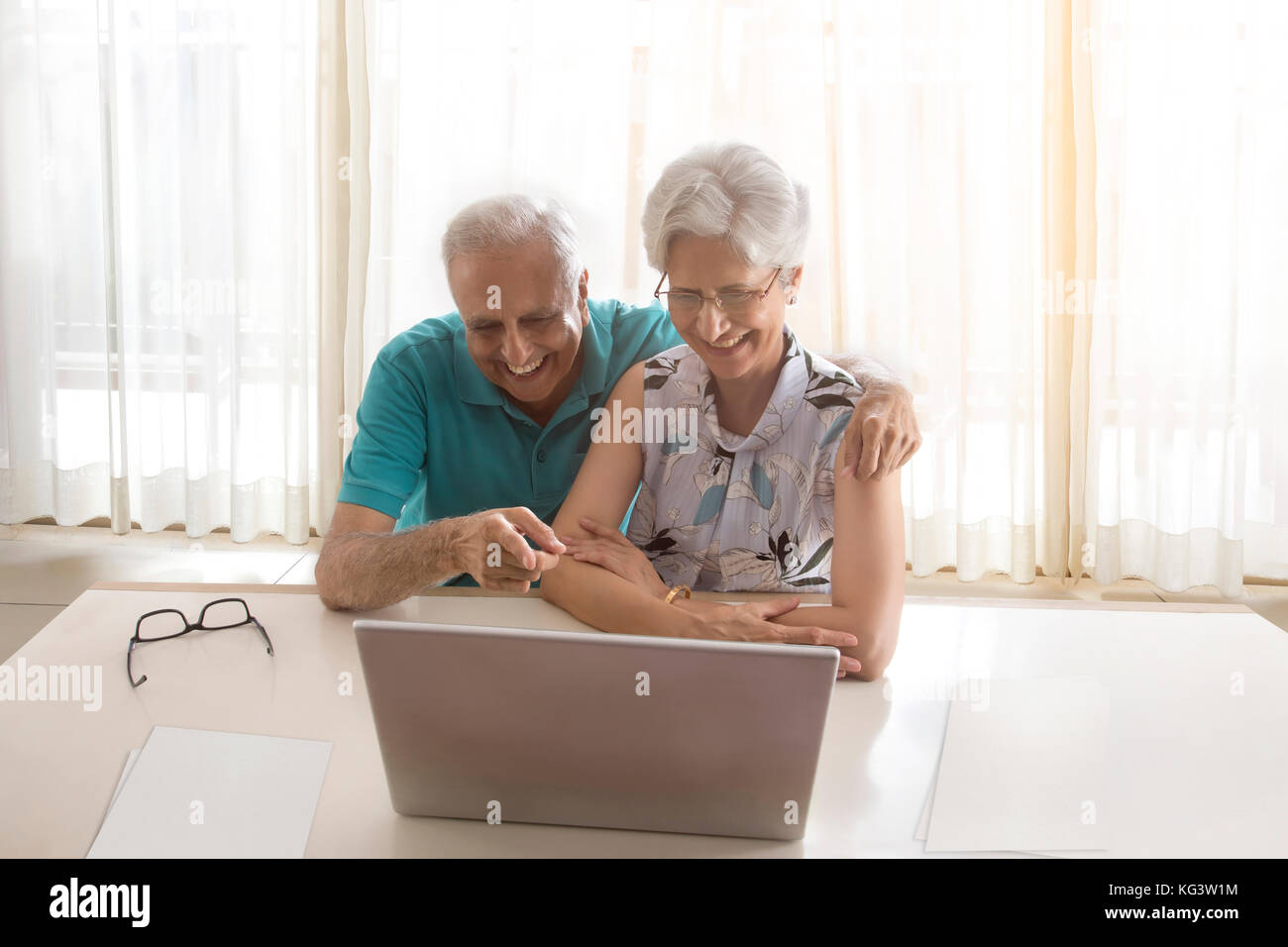 Senior couple using laptop sitting at table Stock Photo
