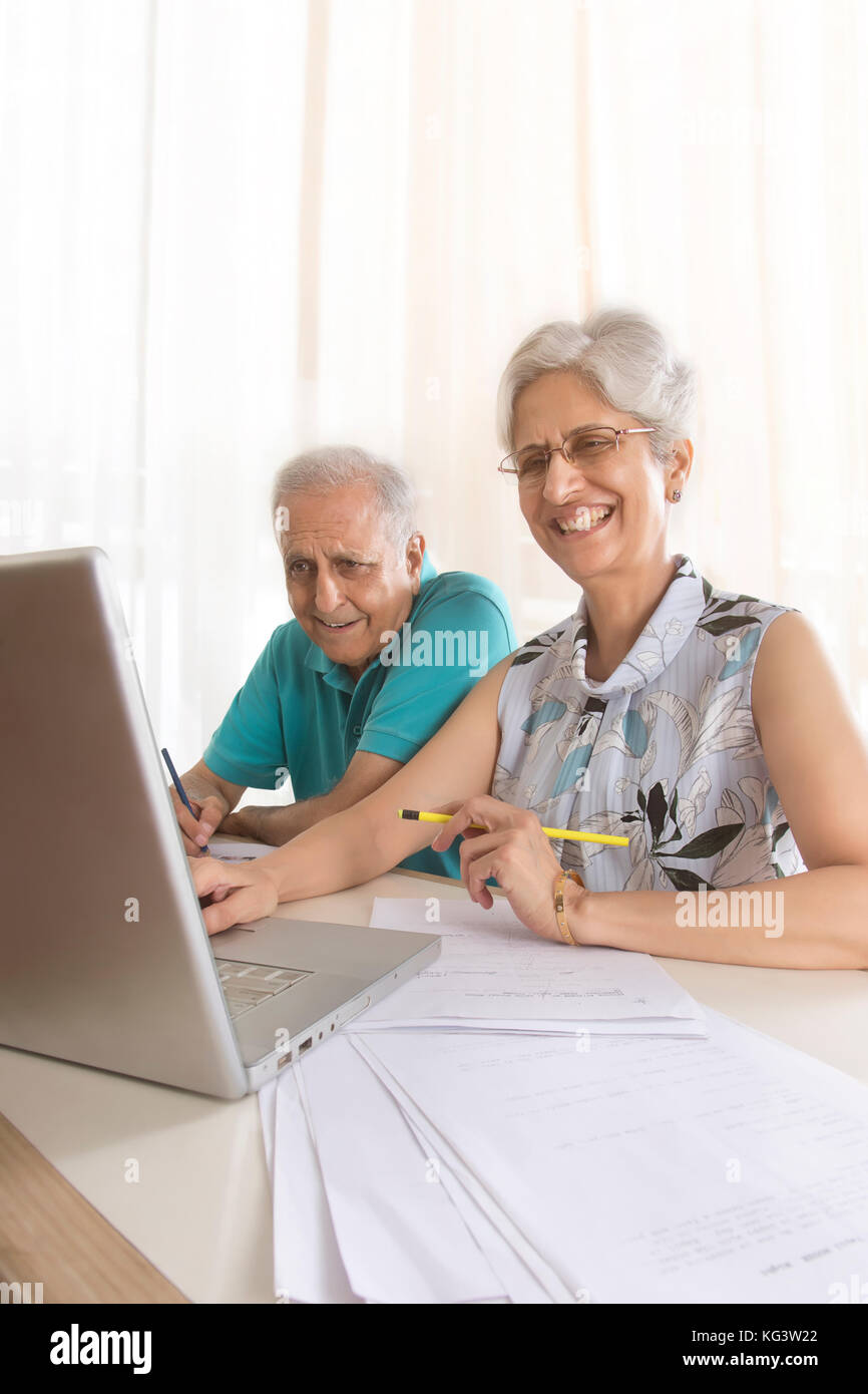 Senior couple doing paper work using laptop Stock Photo
