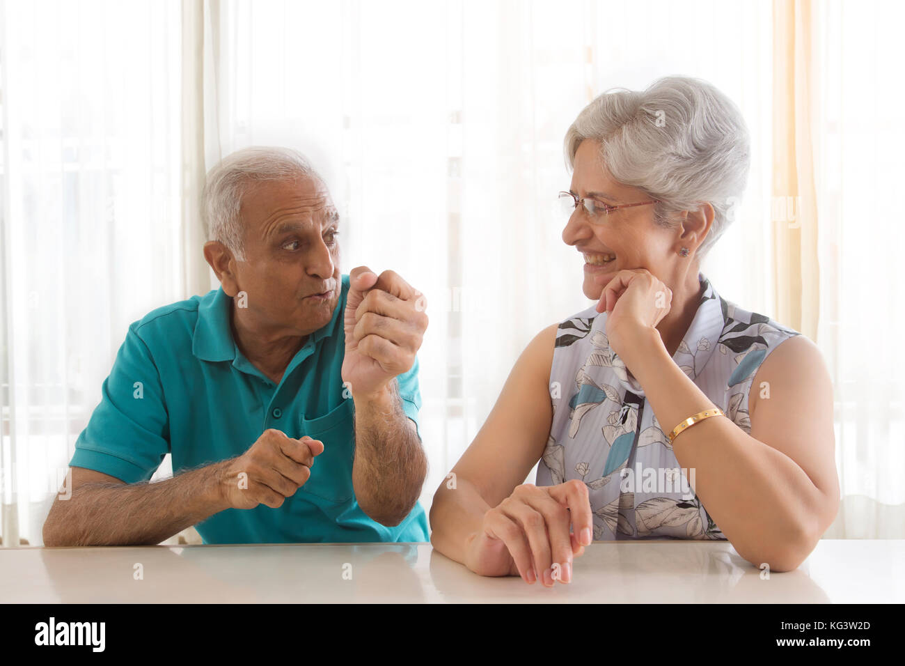 Senior couple talking sitting at table Stock Photo