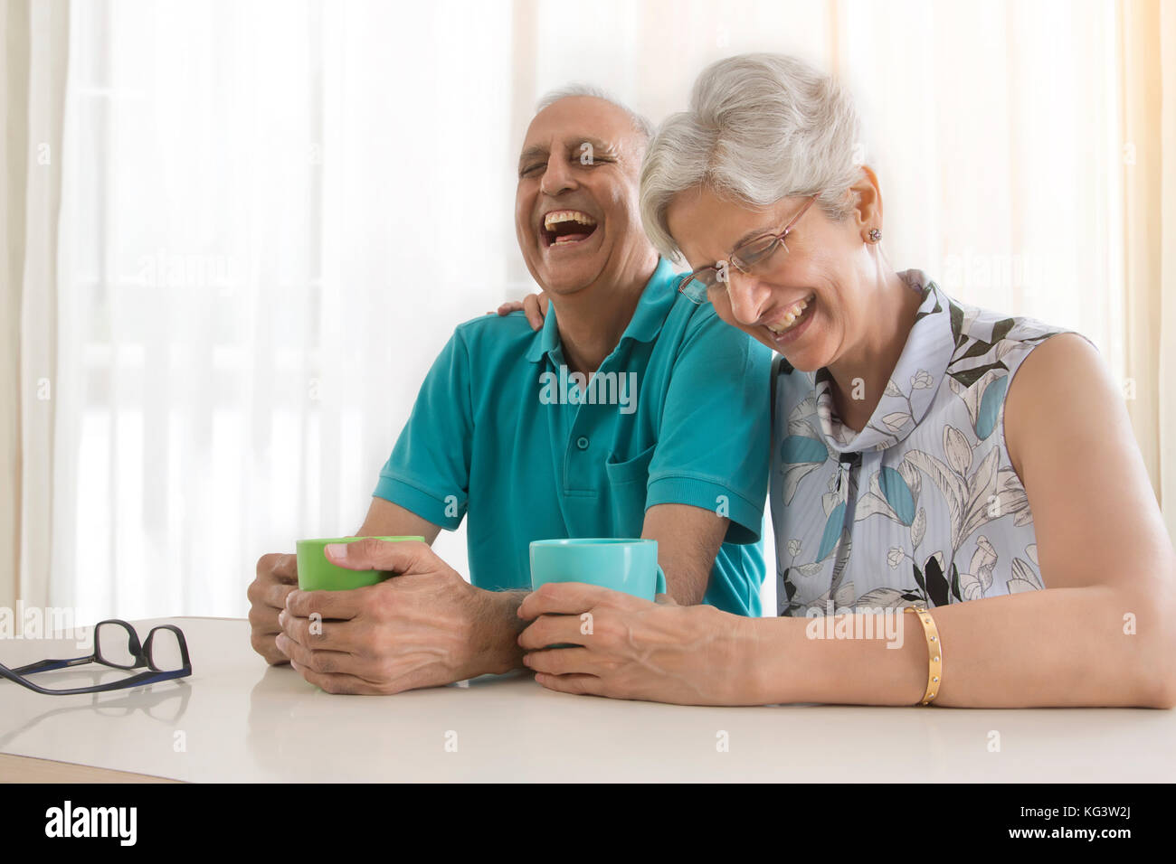 Senior couple laughing while drinking coffee at table Stock Photo
