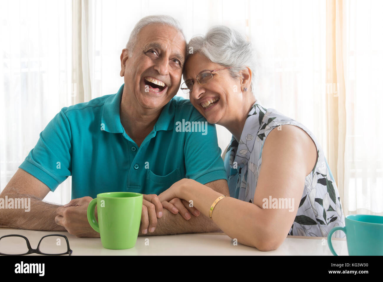Senior couple laughing while drinking coffee at table Stock Photo