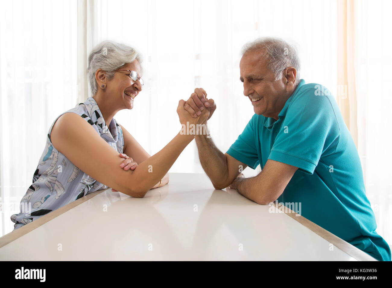 Senior couple arm wrestling at table Stock Photo