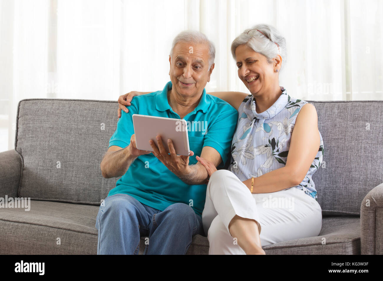 Senior couple using digital tablet sitting on sofa Stock Photo