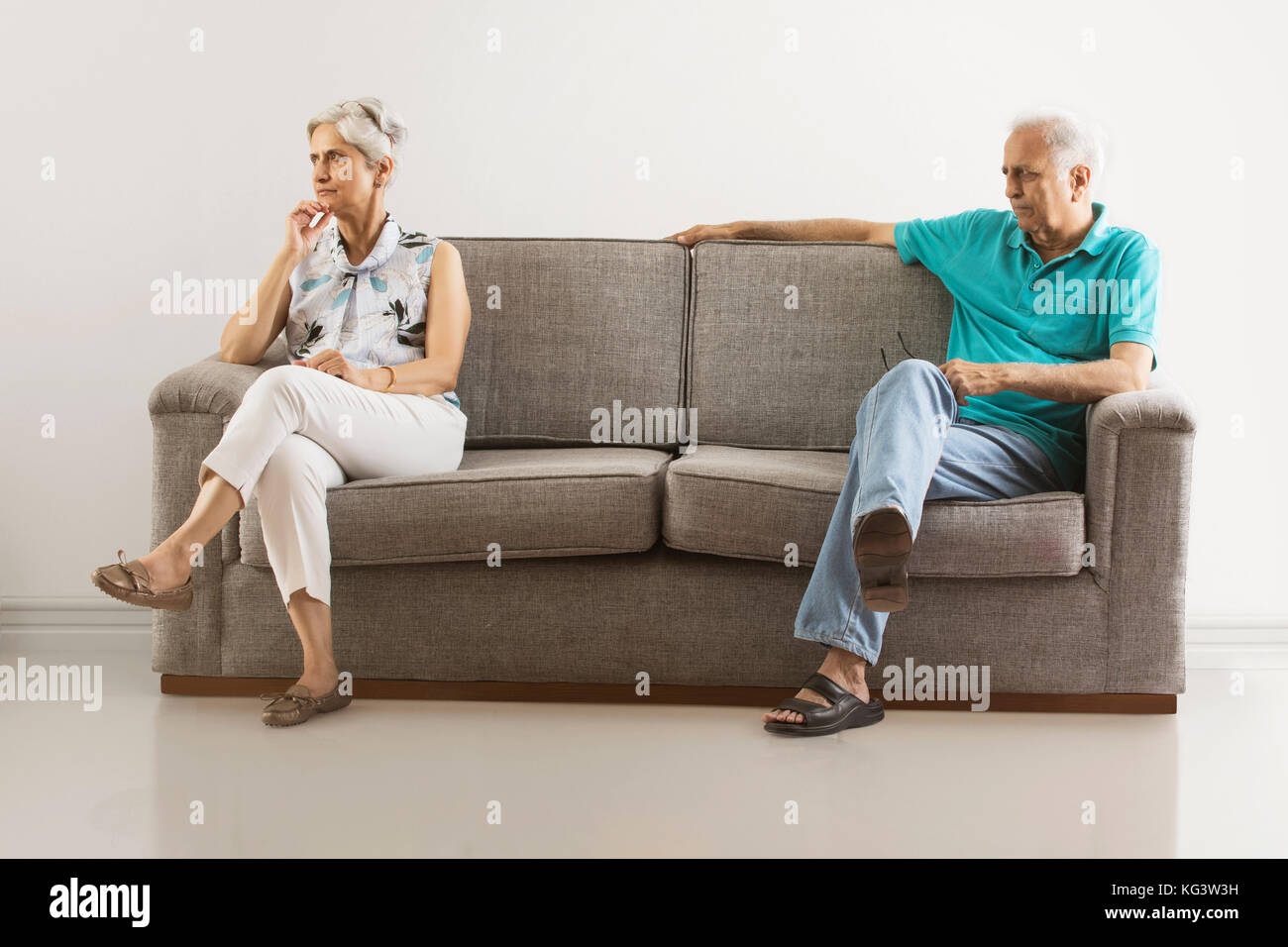 Angry senior couple sitting apart on sofa Stock Photo