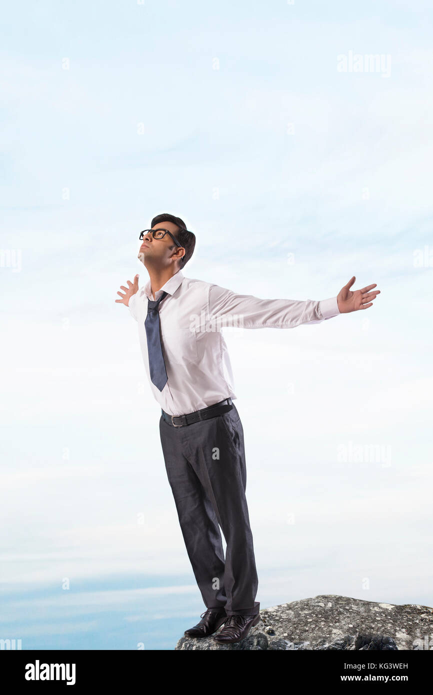Business standing on top of rock with arms outstretched Stock Photo