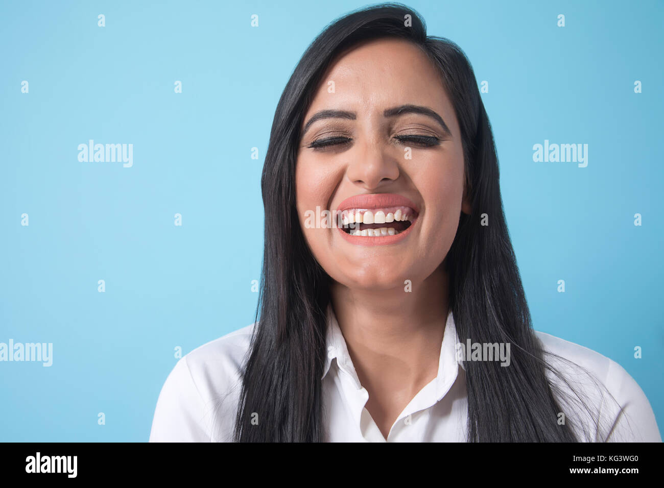 Portrait of smiling young businesswoman over blue background Stock Photo