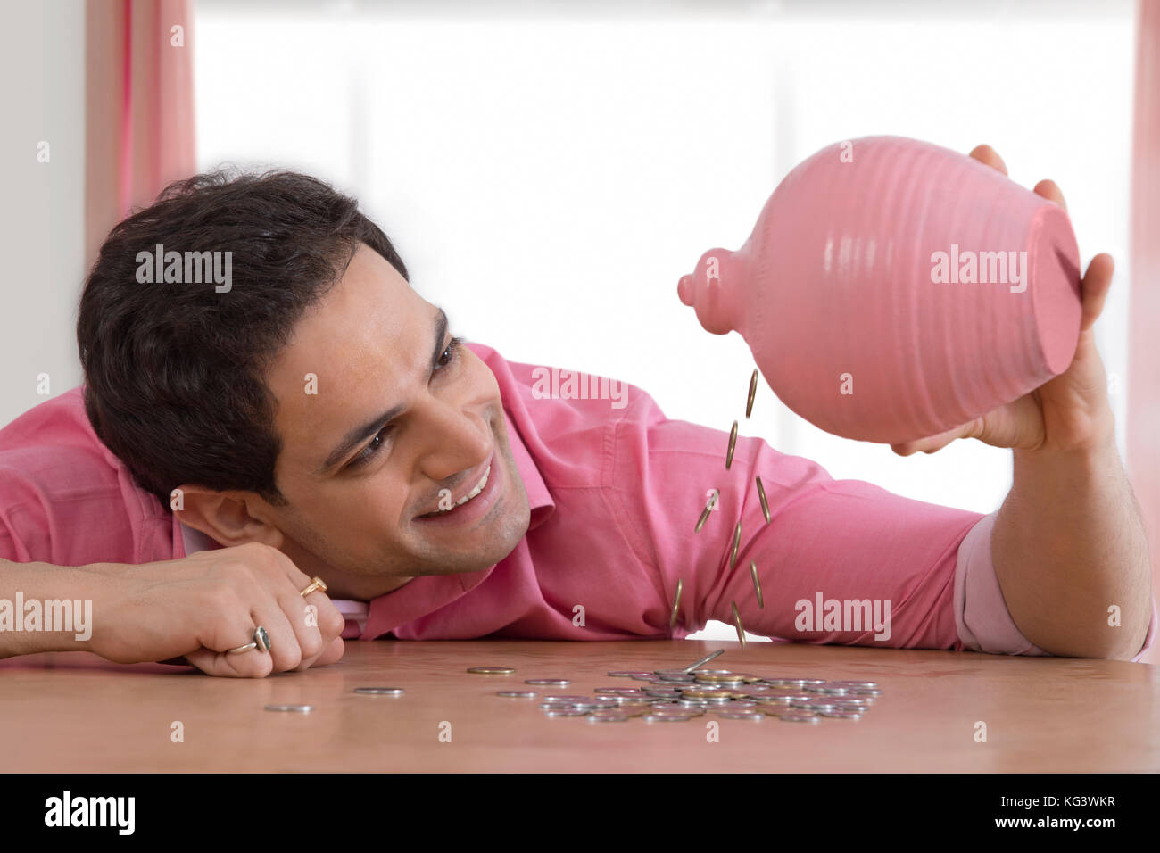 Smiling man emptying piggy bank Stock Photo