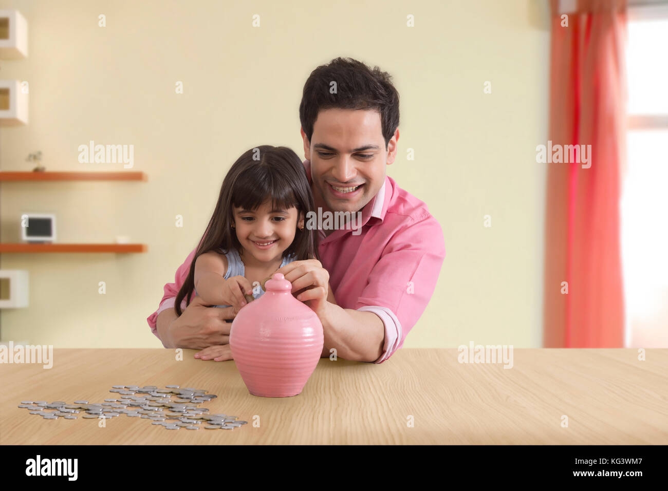 Father and daughter inserting coin in piggy bank Stock Photo - Alamy