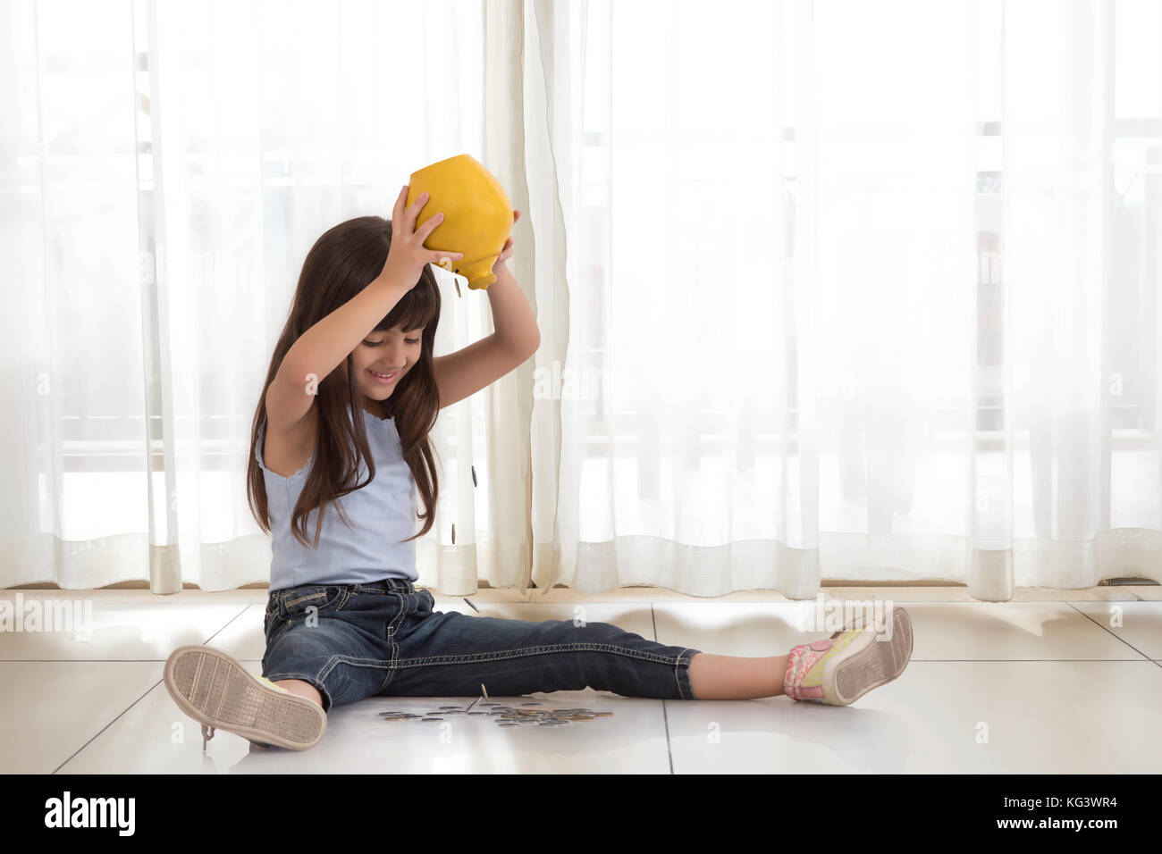 Excited girl emptying coins from piggy bank Stock Photo