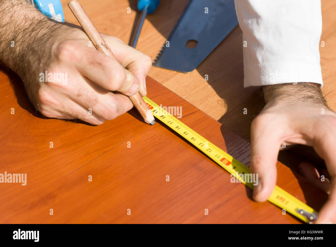 The carpenter measures the distance using a measure and marks with a
