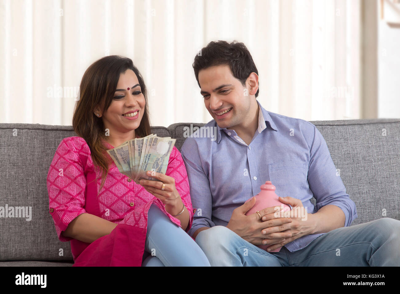 Smiling couple saving money in piggy bank Stock Photo