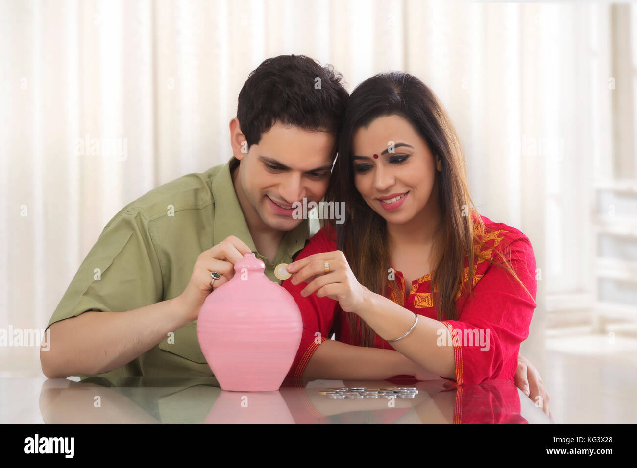 couple inserting coins in clay piggy bank Stock Photo