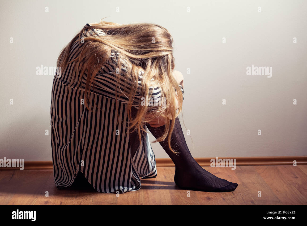 Depressed woman sitting on floor Stock Photo