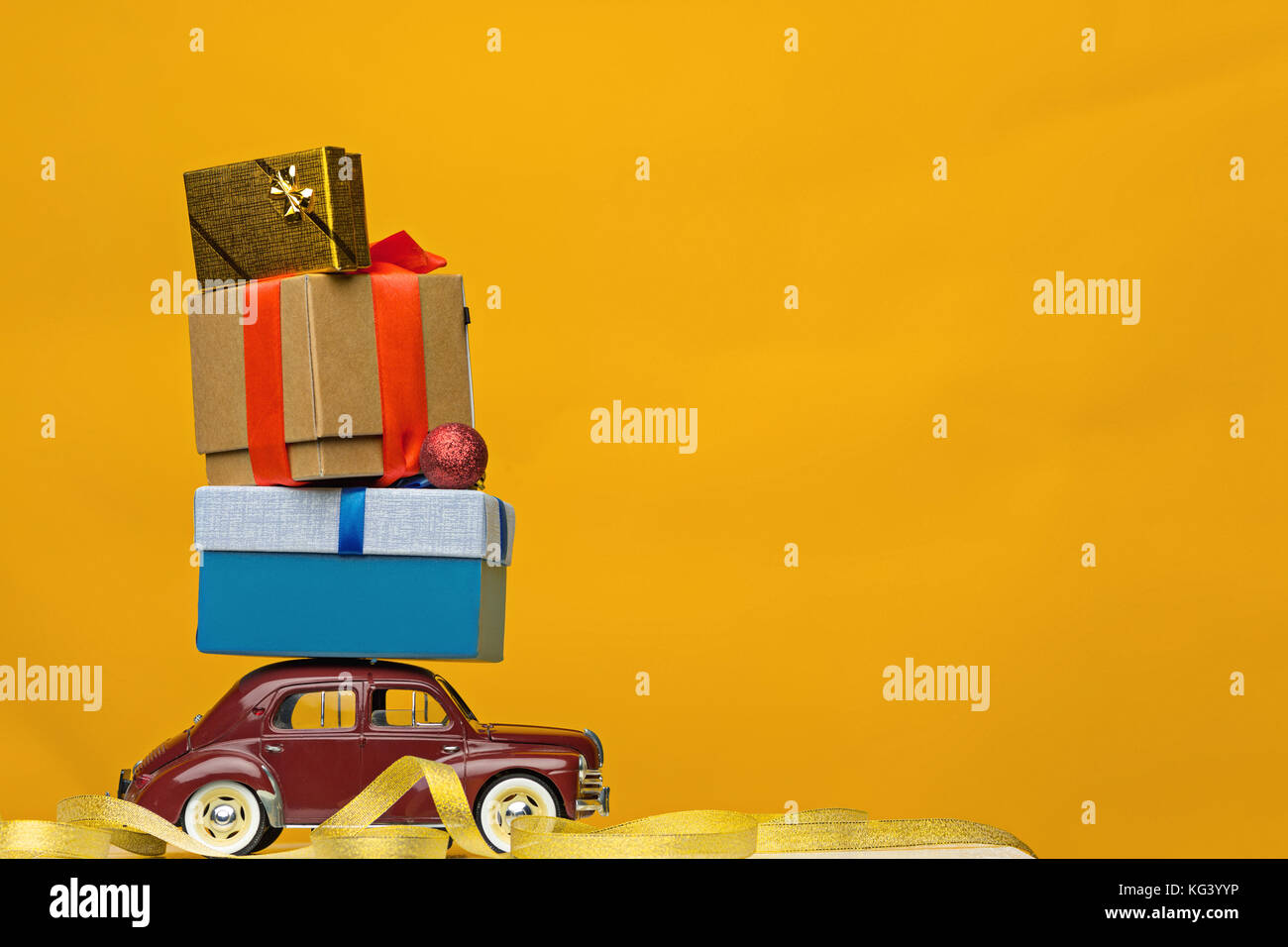 Blue retro toy car delivering Christmas or New Year gifts, on yellow Stock Photo