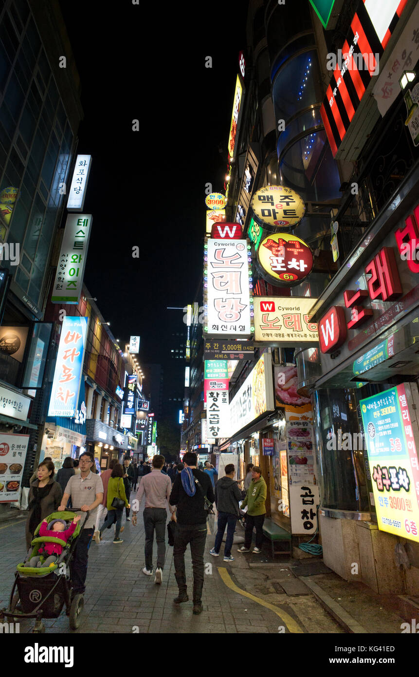 Brightly lit with neon signs the busy night time streets in central Seoul full of residents and tourists enjoying the restaurants and bars Stock Photo