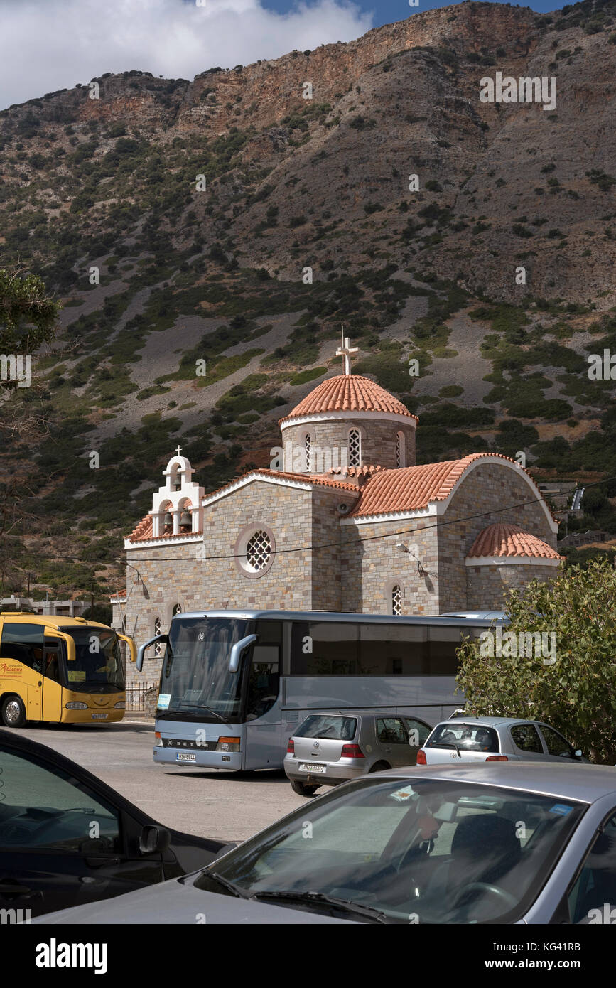 Tour buses and cars parked outside a modern Greek church in the small coastal town of Plaka, Lasithi region of Crete, Greece, October 2017. Stock Photo