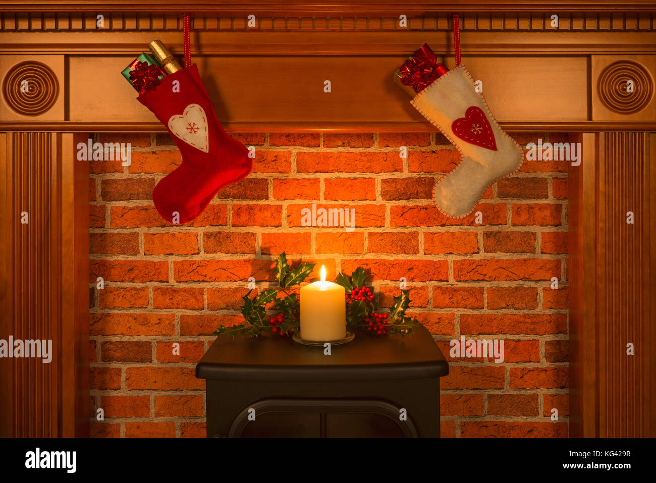 Two Christmas stocking hanging over a fireplace with gifts and a candle. Stock Photo