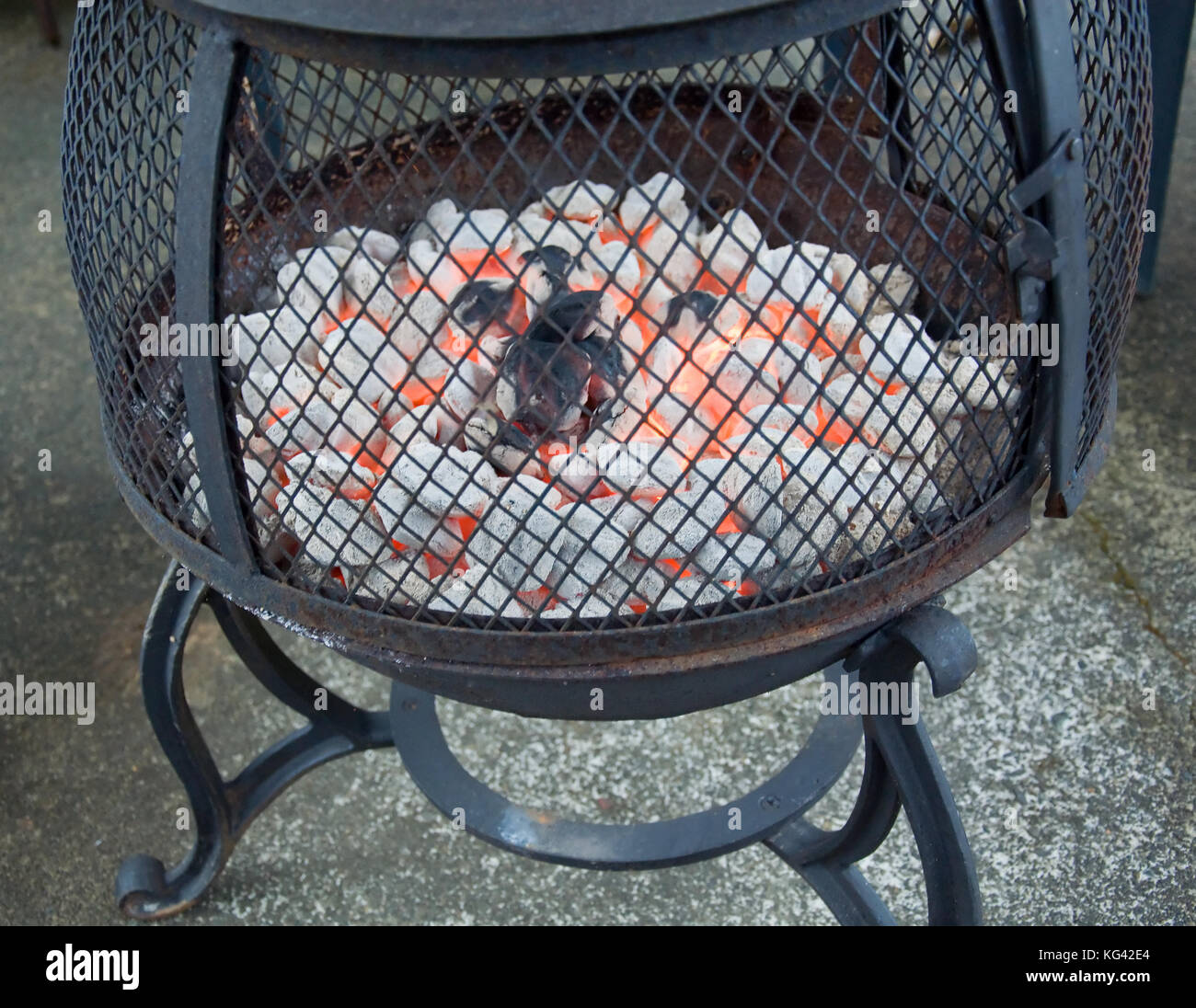 This is a black iron fire pit with red hot burning briquettes going. Stock Photo