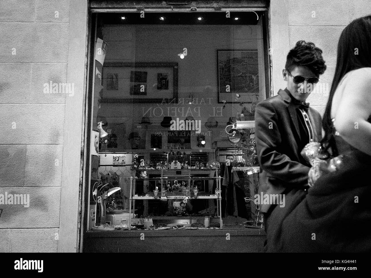 A recently married couple walks by the window of the 'Asi Si' fashion tendency shop that opened at the same space that Calçats Mila occupied years before in the Carme Street of Barcelona, Spain. Date: 07/09/2015. Photo: Xabier Mikel Laburu. The shoe shop Calçats Mila is documented with an other name in 1846. In the beginnings of the XX century, the shop is sold to the Mila family who would take care of it until the death of Roser, the last owner after her brother Joan who would have the tough job to close the shop in 2003. Stock Photo