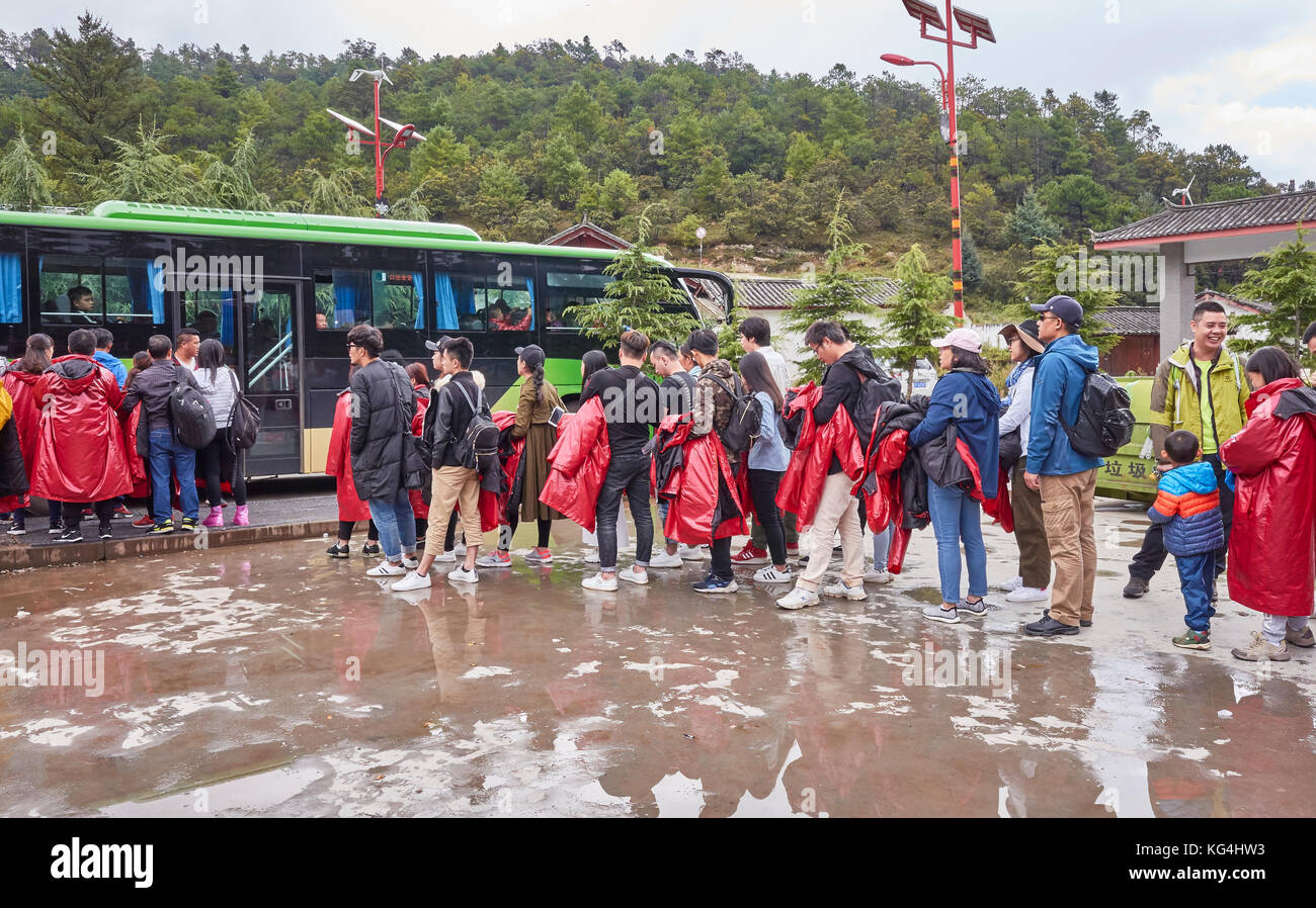 Lijiang, Yunnan, China - September 23, 2017: Tourists wait in line for a bus in Blue Moon Valley scenic area on a rainy day. Stock Photo