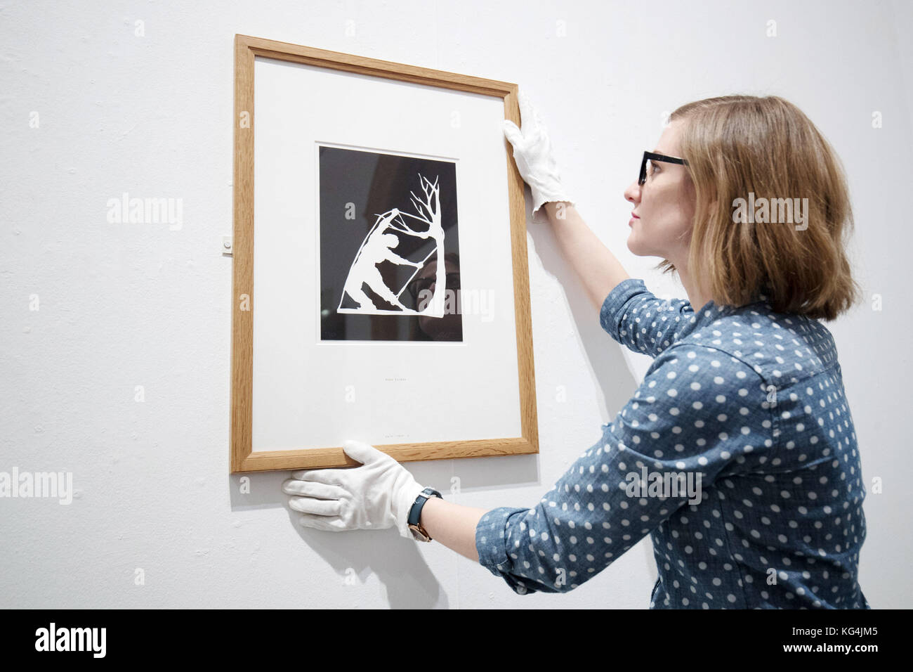Emalee Beddoes-Davis museum curator adjusts Kara Walker's Snared, 2013, on display at the Worcester City Art Gallery and Museum's Warhol to Walker: American prints from pop art to today exhibition. Stock Photo