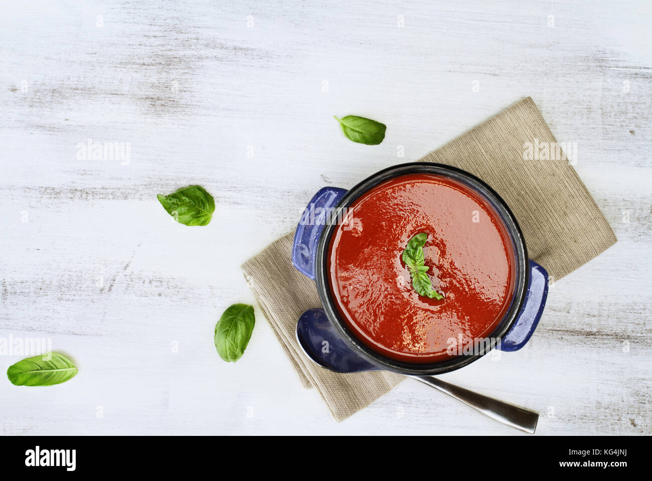 Hot tomato soup with basil leaves. Image shot from above in flat lay style. Stock Photo