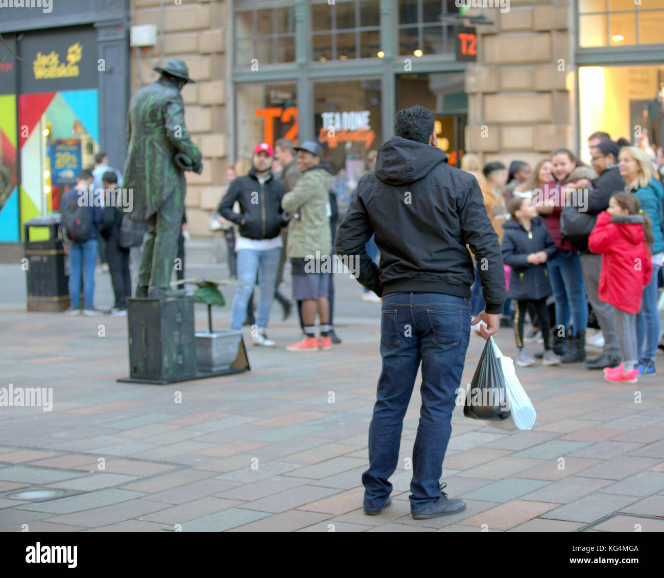 street performer living statue with a posing spectator in crowd on the style mile Glasgow buchanan street viewed from behind Stock Photo