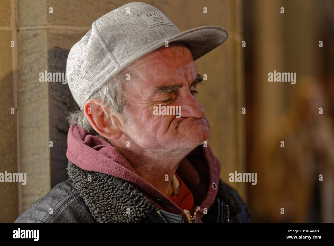 homeless man in glasgow who entertains doing popeye impressions in a baseball hat gurning Stock Photo