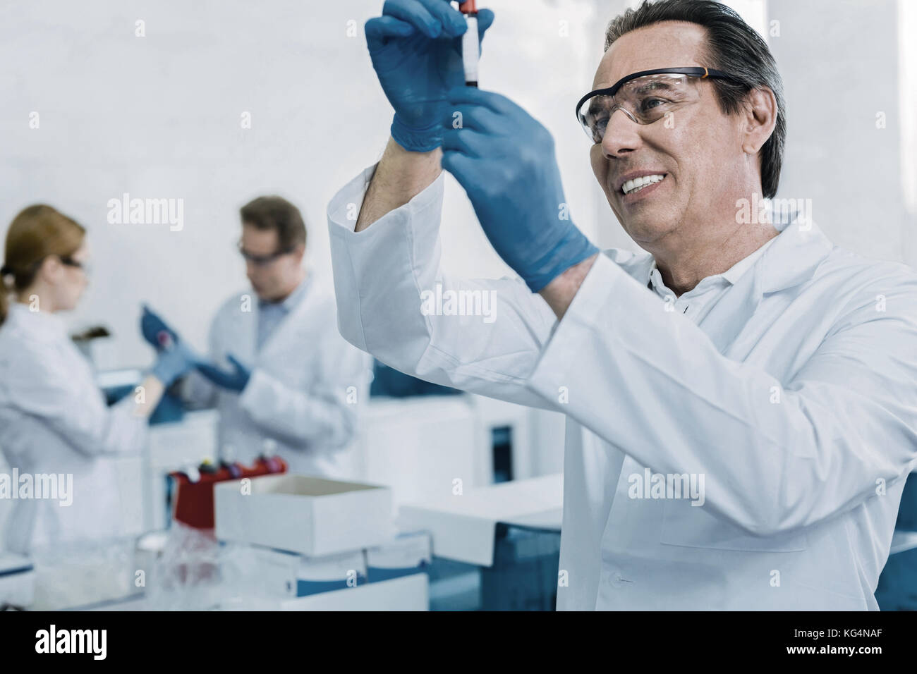 Cheerful nice scientist looking at the test tube Stock Photo
