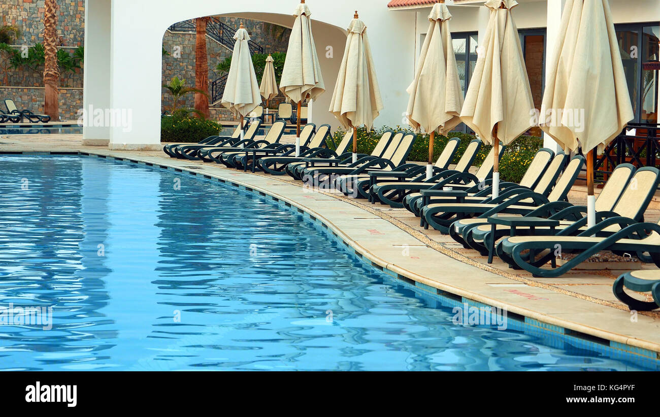 Swimming pool with beach beds and sunshields Stock Photo Alamy